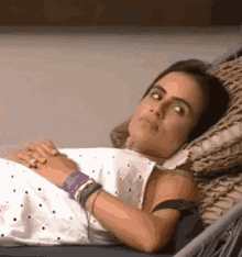a woman is laying in a hammock with a purple wristband