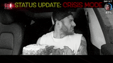 a man is sitting in a car holding a cake and the words status update crisis mode are above him