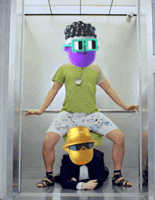 a man in a green shirt is sitting on another man 's lap with a yellow hat that says jvc on it
