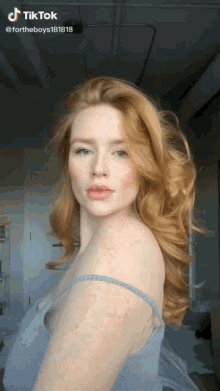 a woman with red hair and freckles is wearing a blue tank top