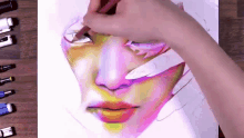 a person is drawing a woman 's face with colored pencils .