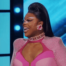 a woman in a pink top and earrings is smiling