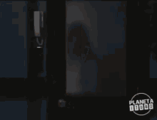 a woman in a white shirt is standing in front of a door with planeta toro written on it