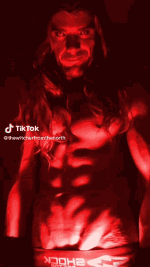 a man with long hair is standing in a dark room with tiktok written on the top