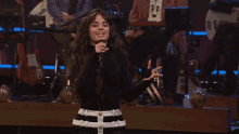 a woman is singing into a microphone on stage