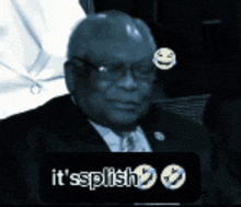 a man in a suit and tie is sitting in front of a sign that says ' it 's splish '