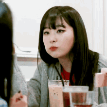 a woman is sitting at a table with a glass of milk and a spoon in her hand .