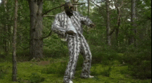 a man in a suit and sunglasses is standing in a forest .