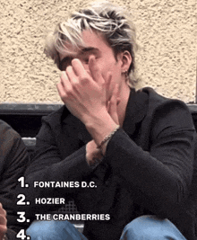 a man covering his face with his hands with the words fontaines d.c. hozier the cranberries and the cranberries next to him