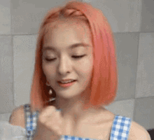 a young woman with pink hair is wearing a blue and white checkered dress and smiling .