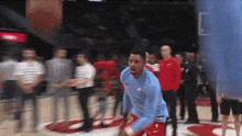 a man in a blue shirt is standing on a basketball court .