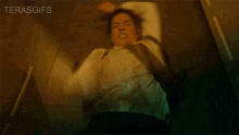 a man in a white shirt and tie is laying on the floor with the words terasgifs behind him