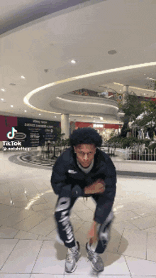 a man is doing a trick in a mall with a tik tok app on his phone .