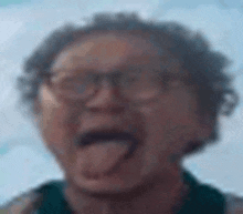 an elderly woman wearing glasses is sticking out her tongue .