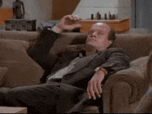 a man in a suit is laying on a couch with his feet up .