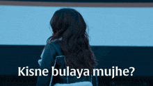 a woman in a black jacket is standing in front of a sign that says kisne bulaya mujhe