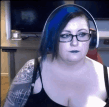 a woman with blue hair and glasses is wearing headphones and a black tank top