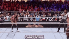 a wrestling match is taking place in front of a crowd at a wrestling ring .