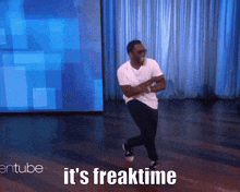 a man is dancing on a stage with the words " it 's freaktime " behind him
