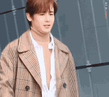 a young man wearing a plaid coat and white shirt