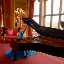 a woman in a blue dress sits in front of a piano