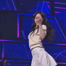 a woman is dancing on a stage in front of a purple and blue background .