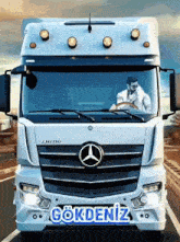 a man is driving a mercedes truck with the word gökdeniz on the front