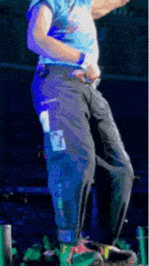 a man in a blue shirt and black pants is standing on a stage .