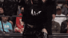 a woman in a black shirt is standing in a ring with her arms in the air .