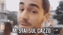 a close up of a man 's face with the words `` mi stai sul cazzo '' written above him .