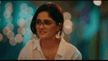 a woman wearing glasses and a white shirt smiles