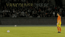 a soccer player kicks a ball in front of a banner for vancouver rise fc