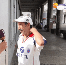 a man wearing a zurich shirt is talking into a microphone