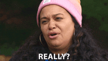 a woman wearing a pink beanie is making a funny face and says really