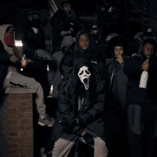 a man wearing a scream mask is being held by a police officer in a store