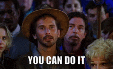 a man in a cowboy hat stands in front of a crowd and says you can do it