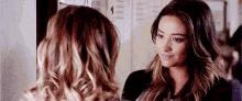 two women are standing next to each other in a locker room looking at each other .