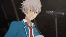 a young man in a blue suit and red tie is standing in front of a microphone
