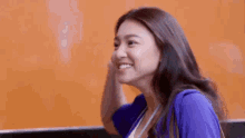 a woman in a blue shirt is laughing with her mouth open and her eyes closed .