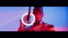 a man in a suit is holding a microphone in front of a red ring