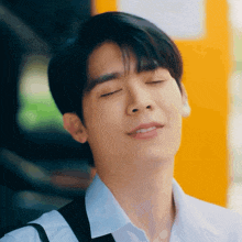 a young man with his eyes closed is wearing a white shirt