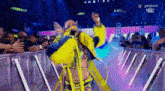 a woman in a yellow and blue outfit is standing in front of a crowd on a stage .