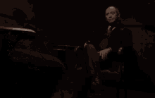 a man in a plaid shirt is sitting in a chair with his eyes closed in a dark room .