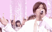 a man singing into a microphone with a group of people behind him