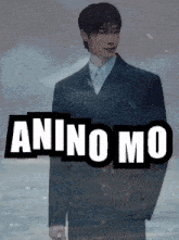 a man in a suit stands in front of a sign that says ' aninomo '