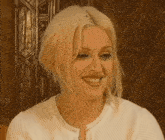 a woman with blonde hair is smiling and wearing a white shirt