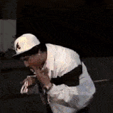 a man wearing a hat with the letter a on it is eating a hot dog .