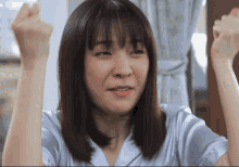 a woman in a white shirt is raising her hands in the air