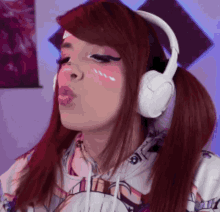 a woman wearing headphones and a hoodie blowing a kiss