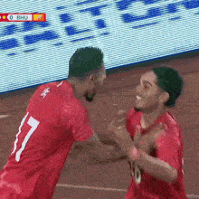 two soccer players wearing red jerseys with the number 7 on the front
